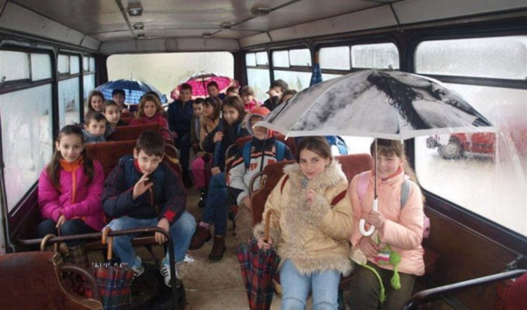 Đaci se u autobusu voze s otvorenim kišobranima