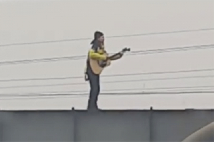 Vozeći rolere svirao gitaru na ogradi mosta